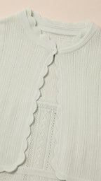Close-up of mint green cardigan showing scalloped trim and knit texture