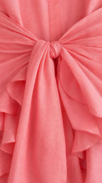 Close-up of the tie-front knot and ruffle hem detail on coral dress