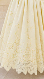 Close-up detail of lace embroidery on yellow dress hem