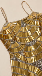 Close-up detail of geometric beadwork and spaghetti straps on gold gown