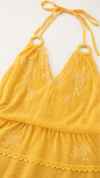 Close-up detail of yellow dress embroidery and halter neckline
