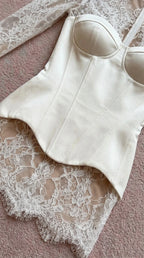 Close-up flat lay detail of white corset bodice and lace hem