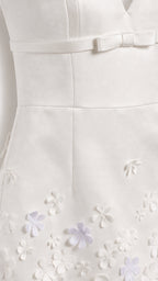 Close-up of white mini dress bodice bow and 3D floral hem