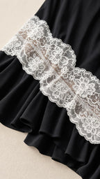 Close-up detail of the cream floral lace trim and black ruffled hem
