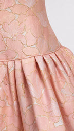 Close-up of pink floral jacquard fabric and pleated skirt detail