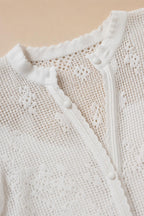 Close-up detail of white crochet lace knit texture and button closure
