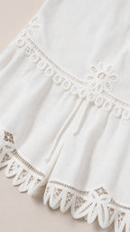 Close-up detail of embroidery and lace hem on white shorts