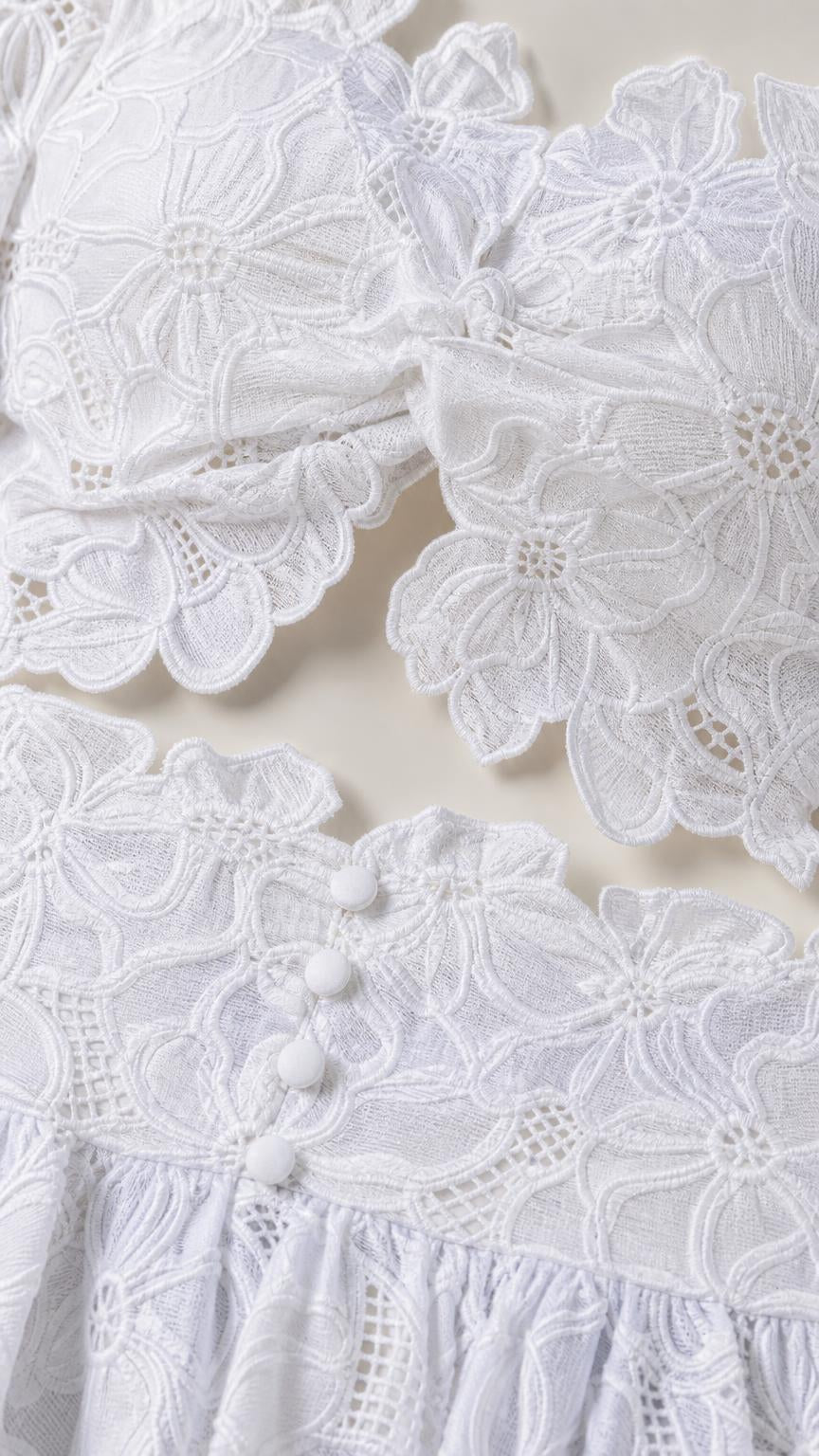 Close-up detail of white floral lace fabric and decorative buttons