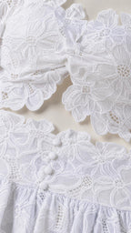 Close-up detail of white floral lace fabric and decorative buttons