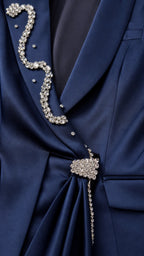 Close-up detail of rhinestone lapel and crystal brooch on navy blazer