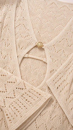 Close-up detail of neckline, ring accent, and knit pattern on beige dress