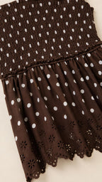 Close-up detail of smocked bodice and eyelet hem on brown dress