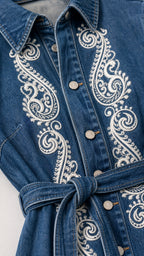 Close-up detail of front button placket and white embroidery