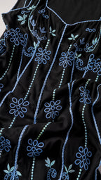 Close-up detail of blue floral embroidery on black fabric