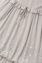 Close-up detail of sequin embellishments and drawstring waist on grey chiffon dress