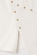 Close-up detail of gold-tone buttons and side hem slit on white dress