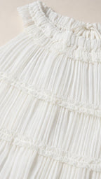 Close-up detail of pleated fabric and neckline on white top