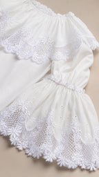Close-up detail of white dress neckline, ruffles, and lace cuffs