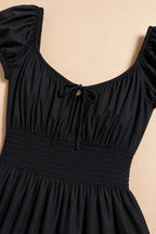 Close-up detail of black dress bodice showing square neckline and smocked waist