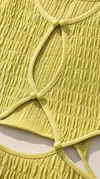 Close-up of olive green dress fabric texture and cutout button details