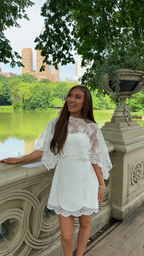 Front view of white lace cape sleeve mini dress with sheer yoke