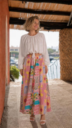 Model wearing white crop top and alternative pink multi printed maxi skirt
