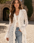 Close-up of white floral lace cardigan showing sheer texture, ruffle front, and flared cuff