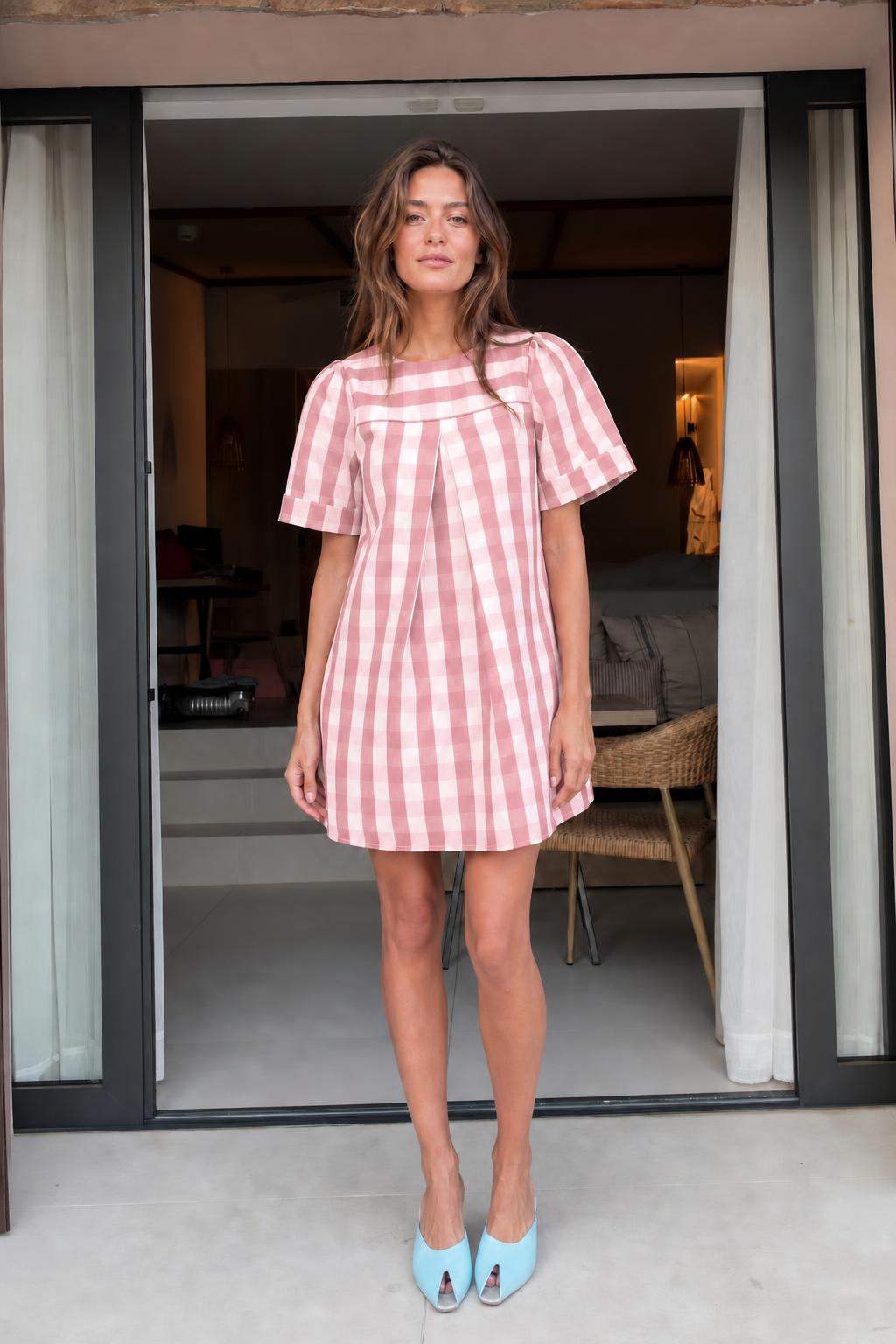 Front view of woman wearing pink gingham check mini dress