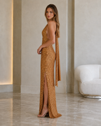 Side view of the gold sequin halter maxi gown with open back detail